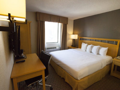 A hotel room with a large bed, desk, and window