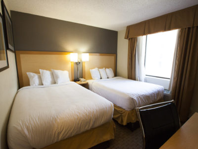 A hotel room with two double beds, a desk, and a window.