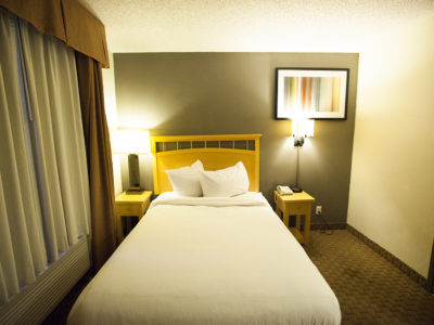 A hotel room with a bed, two nightstands, and a window